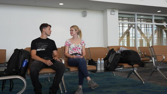 Couple seated in airport waiting area, engaged in conversation and sharing a moment