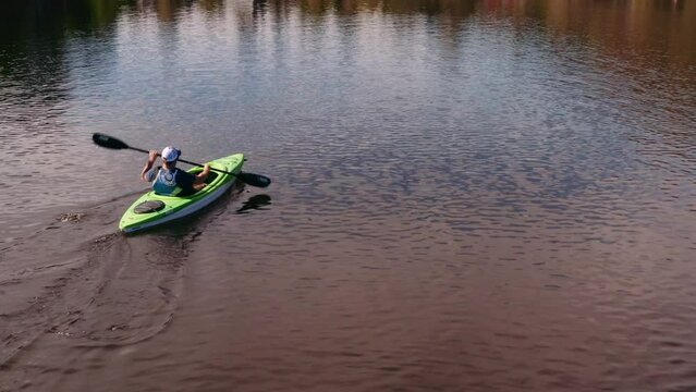 Man in green kayak enjoying time alone on scenic lake. Escalade Quebec kayaking. Drone following guy on water paddling boat.