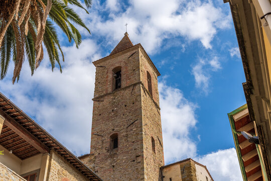 Old stone church tower with a blue sky and palm tree in the foreground