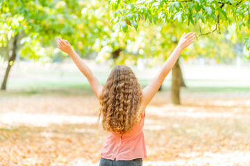 Girl celebrating with her arms in the air and a nice fall back ground