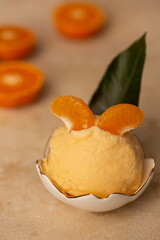 A ball of tangerine ice cream in a creamer