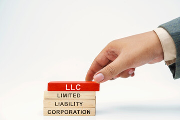 Business hand put wooden block stack with LLC - Limited Liability Company text