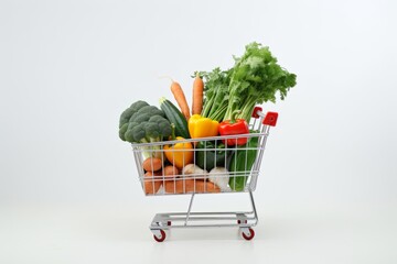 Mini shopping cart filled with fresh vegetables on a white background.