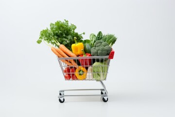 Mini shopping cart filled with fresh vegetables on a white background.