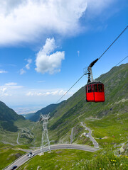 A red cabin rides a cable car in the mountains