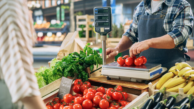 Joyful Local Farmer Running a Small Business, Selling Sustainable Farm Fruits and Vegetables. Bearded Middle Aged Male Welcoming a Female Shopper to Buy a Vine of Tomatoes From an Organic Farm - Powered by Adobe