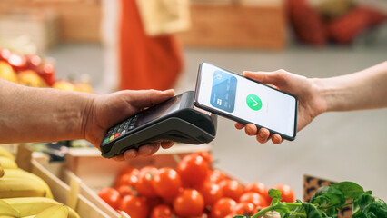 Digital Banking Concept: Shopper Using Mobile Phone with Contactless Payment Technology to Pay for...