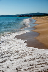 Seascape with beach, waves, foam and empty blue sky