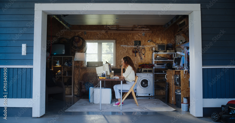 Poster Hispanic Female Developer Programming On Old Desktop Computer In Retro Garage With Random Appliances. Young Woman Working On Innovative Online Service Startup Company In Nineties. Nostalgia Concept.