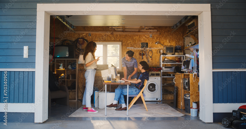 Poster diverse team of three young startup company founders working in retro garage, using old desktop comp