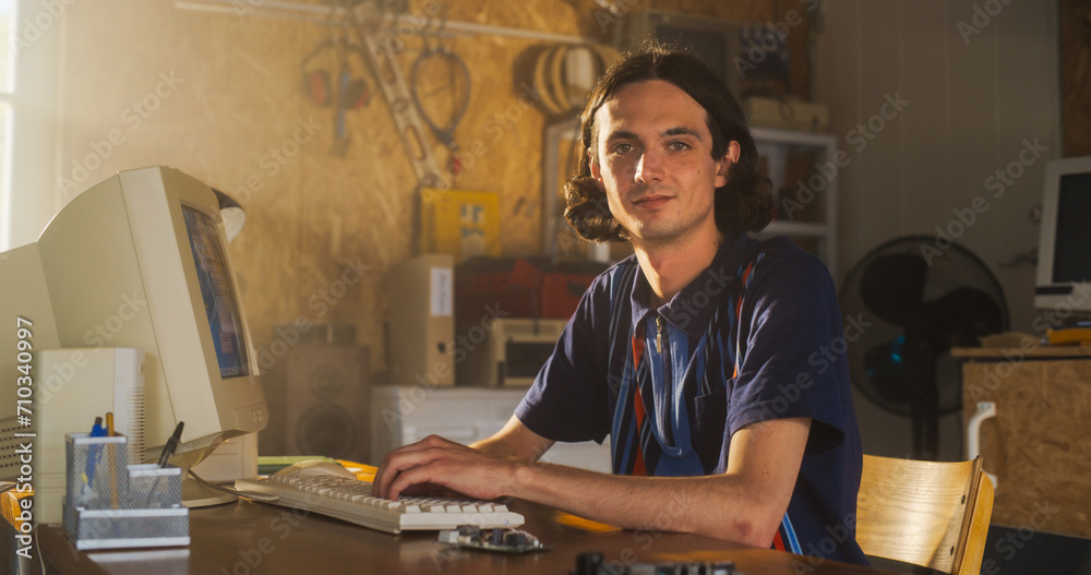 Poster Caucasian Male Software Engineer Programming On Old Desktop Computer In Retro Garage, Looking At Camera And Smiling. Man Starting an Innovative Fintech Startup Company In Nineties. Nostalgia Concept.