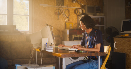 Caucasian Male Software Engineer Programming On Old Desktop Computer In Retro Garage With Random...