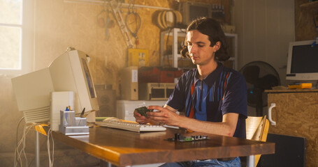 Caucasian Male Computer Engineer Coding On Old Desktop PC And Inspecting Microchip In Retro Garage. Man Starting an Innovative Computer Company In Nineties, Building New Devices. Nostalgia Concept.