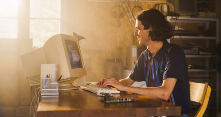 Caucasian Male Software Engineer Programming On Old Desktop Computer In Retro Garage With Random...