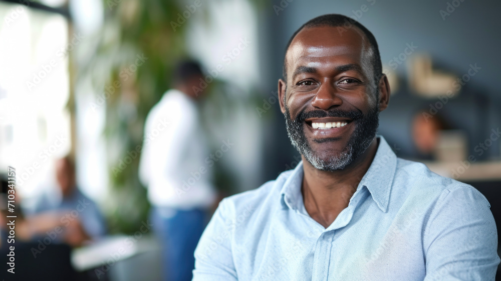 Wall mural Portrait of a handsome smiling black businessman boss standing in his modern business company office.