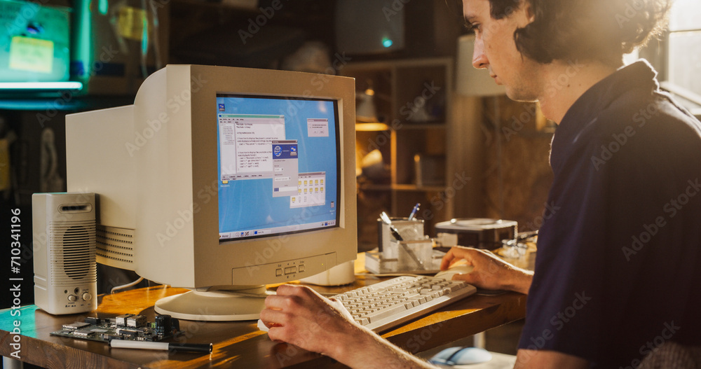 Fototapete Caucasian Male College Student Using Old Desktop Computer In Nineties Retro Garage. Young Programmer Connecting World Wide Web Via Early Internet Software, Exploring Global Network.