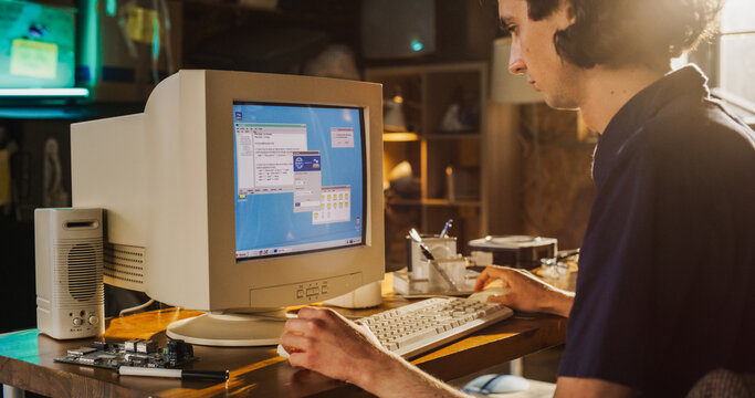 Caucasian Male College Student Using Old Desktop Computer In Nineties Retro Garage. Young Programmer Connecting World Wide Web Via Early Internet Software, Exploring Global Network.