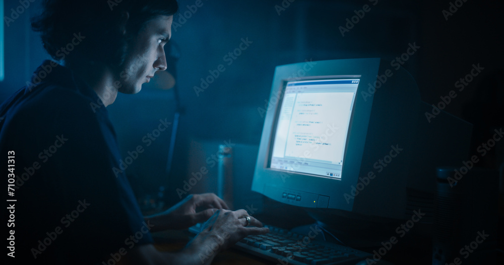 Poster Caucasian Male Web Designer Using Old Desktop Computer In Retro Garage Late At Night. Focused Internet Enthusiast Writing Code At Home. Programming Successful Social Network Website In Nineties.