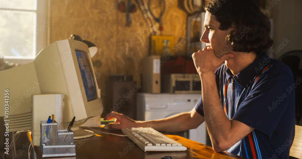 Aufkleber Portrait Of Caucasian Male Software Engineer Programming on Old Desktop Computer In Retro Garage In The Evening. Man Starting Tech Startup Company In Nineties. Coding Innovative Online Service At Home