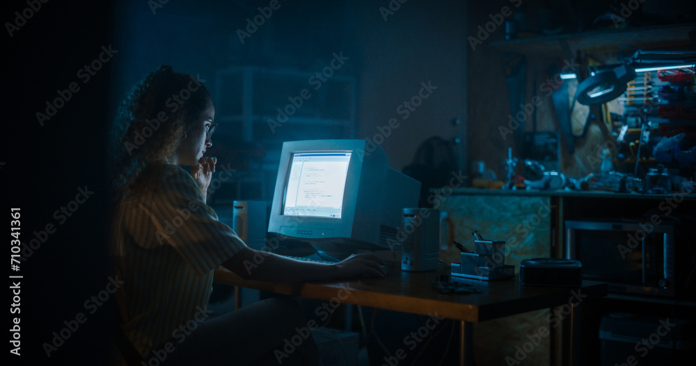 Leinwandbilder Hispanic Female Programmer Using Old Desktop Computer In Retro Garage Late At Night. Evil Hacker Searching For Software Vulnerabilities, Doing DDOS Attack, Coding Trojan Horse Programs, Stealing Data.