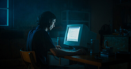 Caucasian Male Web Designer Using Old Desktop Computer In Retro Garage Late At Night. Focused Internet Enthusiast Writing Code At Home. Programming Successful Online Forum Website In Nineties.