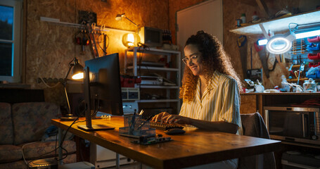 Portrait of Hispanic Female Software Engineer Programming on Desktop Computer In Retro Garage Late...