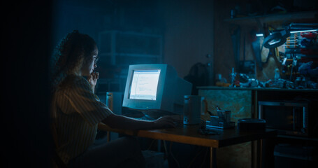 Hispanic Female Programmer Using Old Desktop Computer In Retro Garage Late At Night. Evil Hacker Searching For Software Vulnerabilities, Doing DDOS Attack, Coding Trojan Horse Programs, Stealing Data.