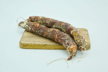 Dried sausages lie on a wooden board. The product is ready to use. White background.