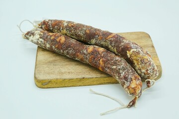 Dried sausages lie on a wooden board. The product is ready to use. White background.