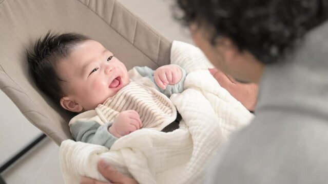 Video of a smiling and laughing Asian baby with a cute smile that his father is caring for.Gentle fathers raising their children.