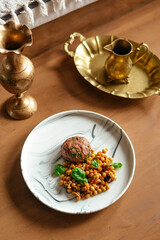 beef patty on a plate with a side dish of chickpeas and sauce