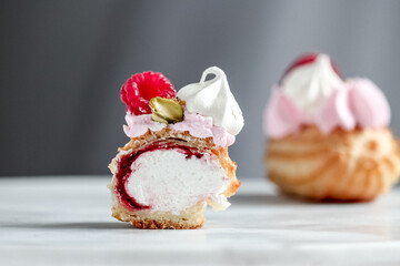 Close up of cut open eclairs filled with cream, jam and fruit topping