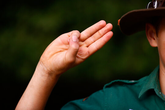 Boy scout in uniform performs three finger salute. Scout symbol hand gesture. France.