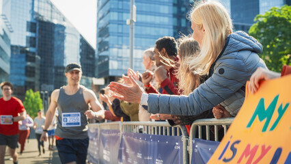 Portrait of a Male Marathon Runner Giving a High Five to Female Family Member in the Audience While...