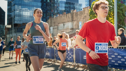 Shot of Group of Diverse People Running in a Marathon with the Cheers of their Loved Ones and...
