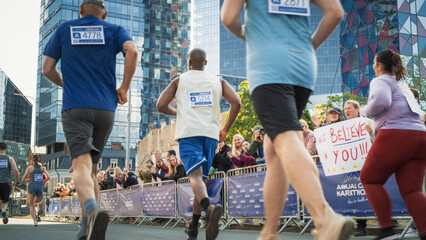 Shot of a Group of Diverse People Running in a Marathon and Waving to their Loved Ones and Supporters in the Audience. Runners Participating in a Charity Run to Raise Money a Cause