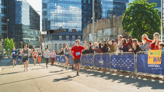 Diverse Group of People Competing in a Marathon Race in the City. Family and Friends in the Audience Cheering Enthusiastically and Supporting Their Loved Ones
