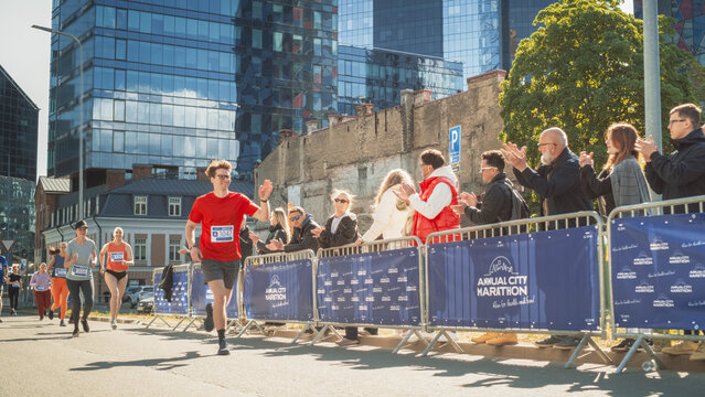Diverse People Running in a Marathon and Waving to their Loved Ones and Supporters in the Audience. Runners Participating in a Charity Run to Raise Money a Cause