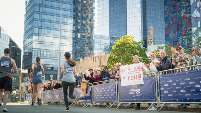 Back View: Diverse Group of Marathon Joggers Competing for the First Place, Running in a City Trail  Audience Clapping and Cheering Their Loved Ones Who are Participating in the Race