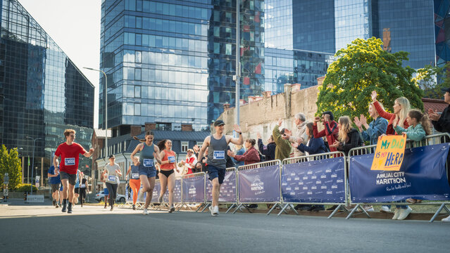Shot of a Group of Diverse People Running in a Marathon and Waving to their Loved Ones and Supporters in the Audience. Runners Participating in a Charity Run to Raise Money a Cause