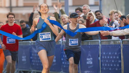 Portrait of Athletic Female Jogger Crossing the Finish Line in Marathon Race with the Audience...