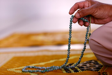 Muslim man praying with islamic prayer beads. Close-up on hand. Vietnam.