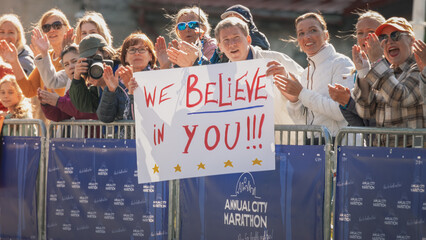 Marathon Supporters Waving at Their Loved Ones During a Sprint. Audience Members Holding...