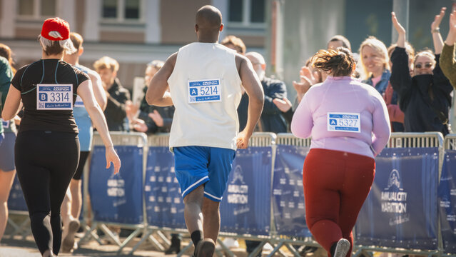 Close Up on the Back of a City Marathon Runners With Signs with Numbers. Diverse Marathon Runners Competing for the First Place in a Race, Waving at their Loved Ones in the Audience - Powered by Adobe