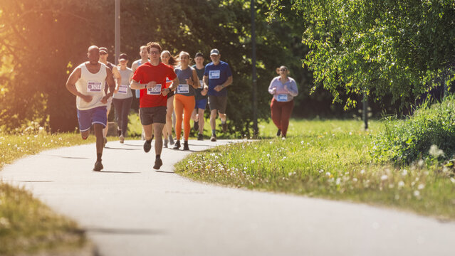 Wide Shot of Diverse Marathon Participants Competing in a Race for the Finish Line: Group of People Running Through Park Health Trail and Participating in a Marathon with Dedication - Powered by Adobe