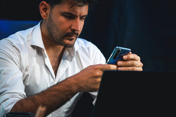 Working businessman using smartphone with customer or coworker to send email at neon workplace,...