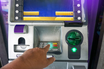 Close up of hand entering code at atm machine