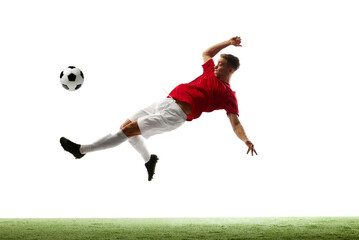 Elevated excellence. Soccer maestro kicks ball into air, showcasing skill and finesse against white studio background with green grass. Concept of sport games, energy, world cup season, movement. Ad