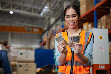 factory worker smiling and counting cash money in the warehouse storage