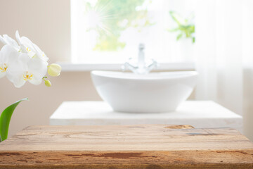 Wooden table top with copy space on blurred bathroom sink and window background